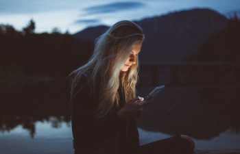 A woman looking at her phone screen, with lake background